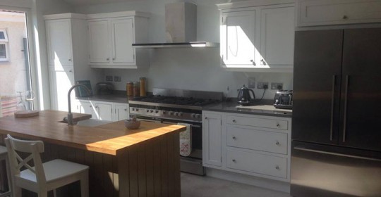 Kitchen with white shaker cabinets and walnut island