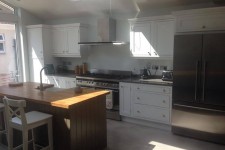 Kitchen with white shaker cabinets and walnut island