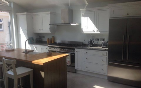 Kitchen with white shaker cabinets and walnut island